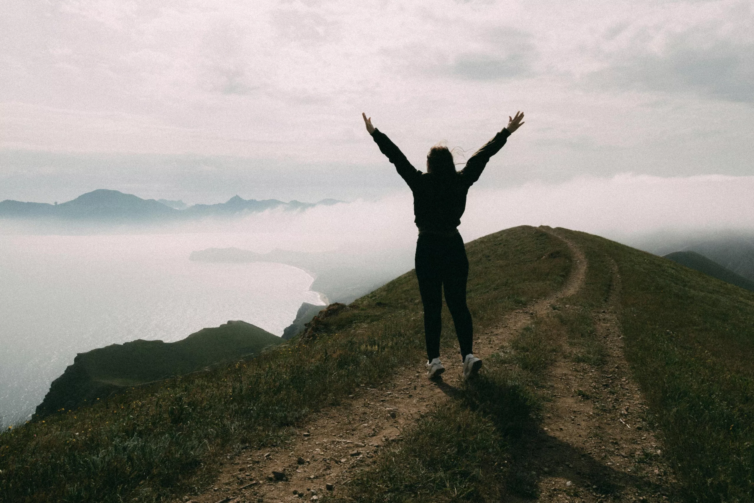 Femme qui lève les bras au ciel pour exprimer son sentiment de liberté